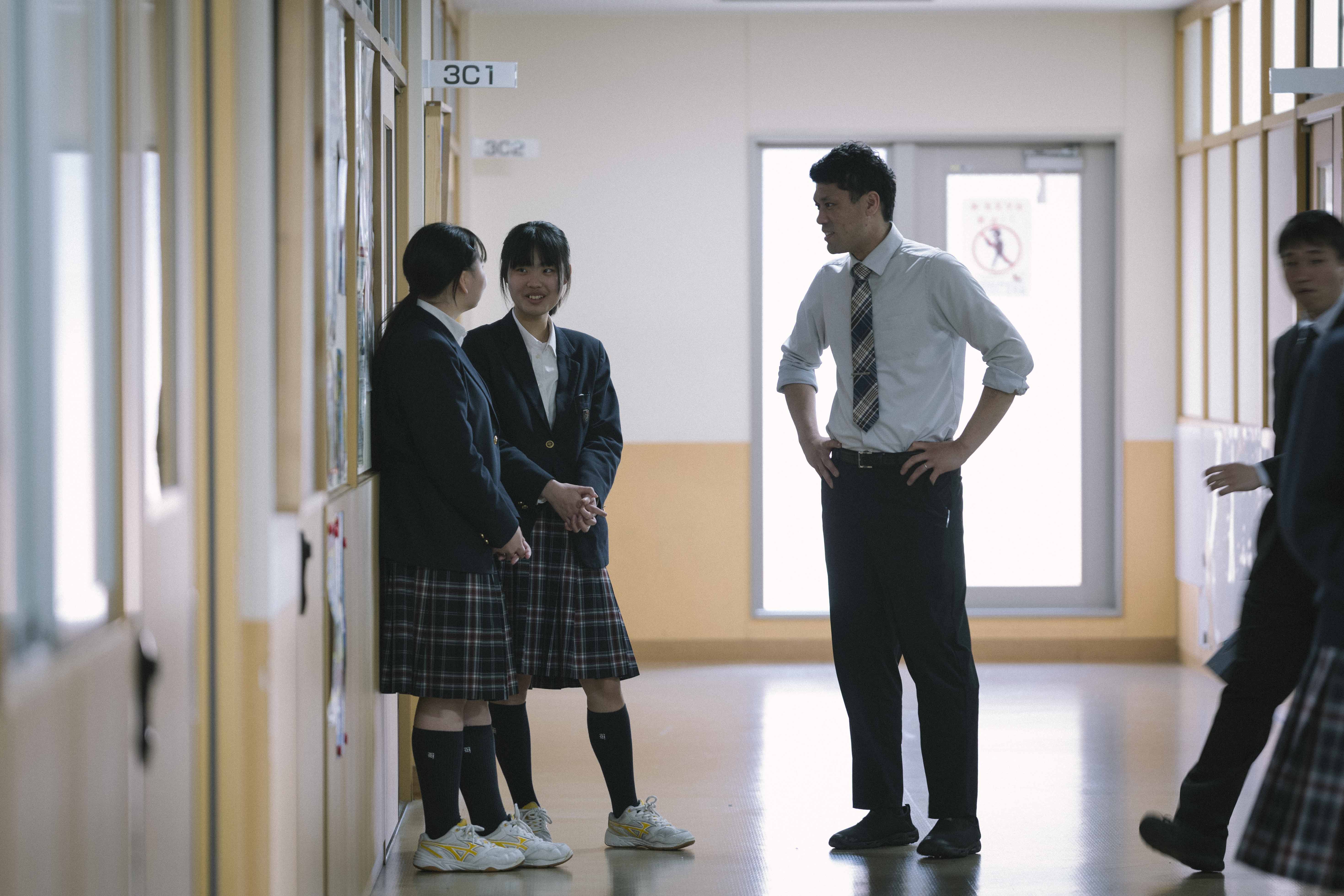 廊下で先生と生徒が会話する様子